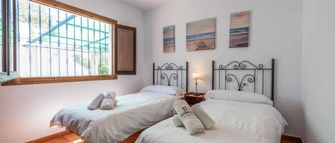 Habitación de hotel con dos camas, una ventana que da a las vistas exteriores y tres cuadros en la pared.