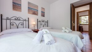 Une chambre d’hôtel avec deux lits, une table de chevet avec une lampe et des œuvres d’art accrochées au mur.