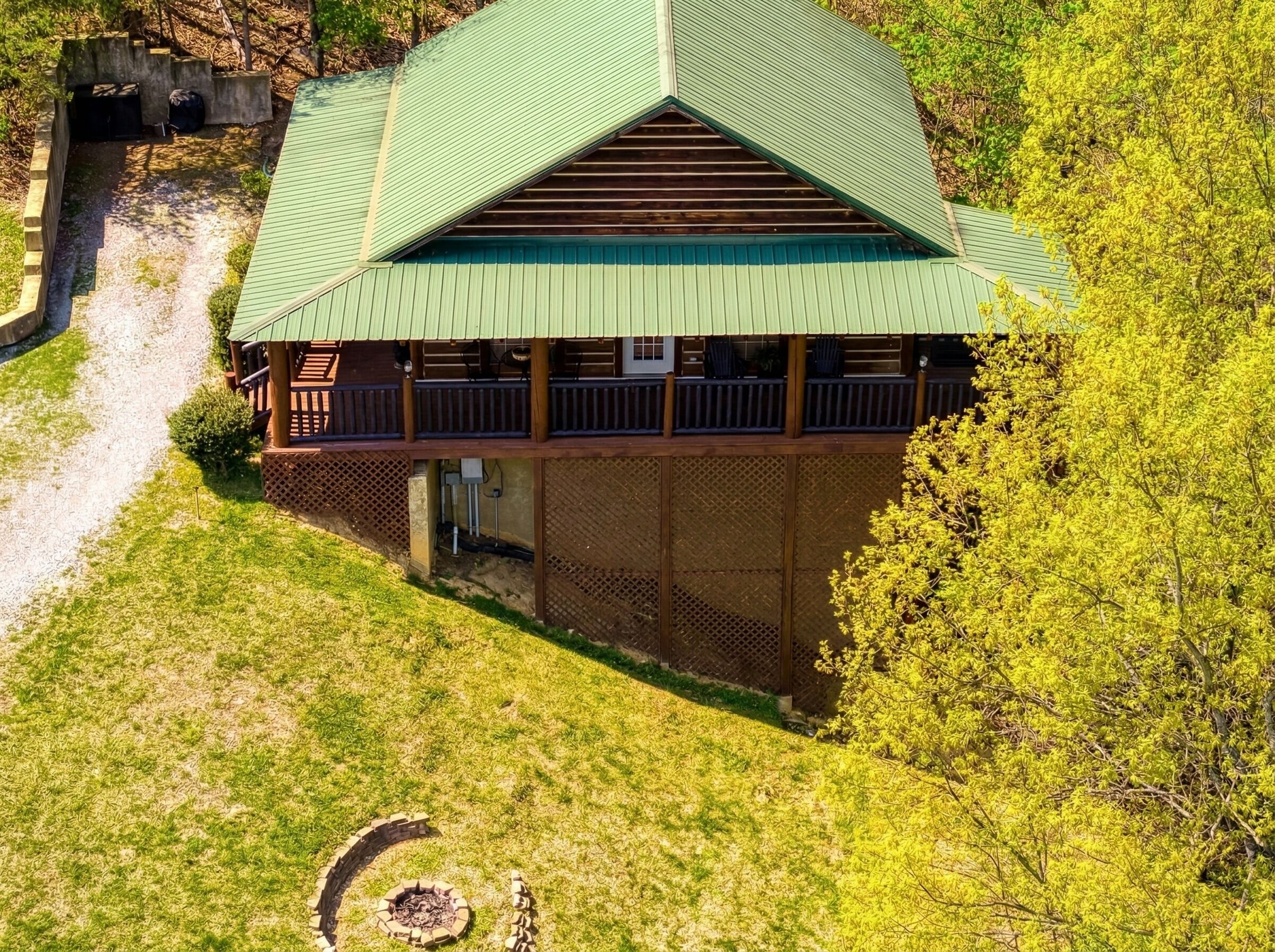 Een lodge met een groen dak, een overdekt terras en een vuurkuil.