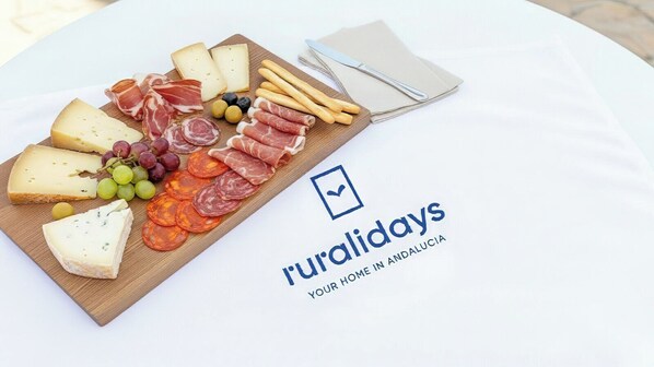 A charcuterie board with various cheeses, meats, and grapes on a wooden board, with a napkin and a knife on the table. - Apartamento Brisa Almayate Alto by Ruralidays (Málaga)
