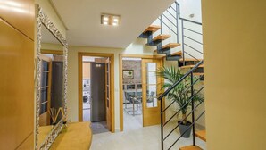 Een modern interieur met een trap, een eethoek en een keuken die door een open deur zichtbaar is.