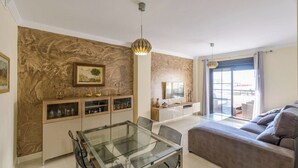 Een moderne woonkamer met een glazen eettafel, een bank en een televisie.