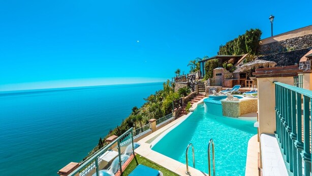 A pool area with a view of the ocean, a staircase leading to a terrace, and lounge chairs. - Ventanas al Mediterráneo Nerja by Ruralidays (Málaga)