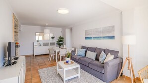A modern living room with a grey sofa, white coffee table, and a dining area with a white table and chairs. - Ventanas al Mediterráneo Nerja by Ruralidays (Málaga)