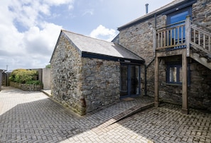 A stone building with a wooden staircase leading to a balcony.
