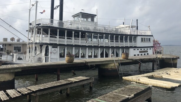 Un barco de paseo fluvial con exterior blanco, varias cubiertas y una bandera.