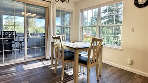 A dining area with a table and chairs, large windows, and a chandelier. - Rf12 Flathead River Haven (Columbia Falls)