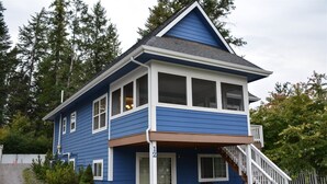 A two-story house with a blue exterior, white trim, and a front porch with a staircase. - Rf12 Flathead River Haven (Columbia Falls)