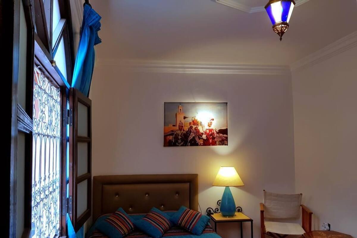 Une chambre à coucher avec un lit, une table de chevet avec une lampe, une chaise et un tableau au mur.