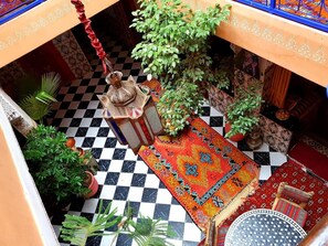 A checkered floor with a patterned rug, potted plants, and a hanging lantern. - Riad Konouz (Marrakech)