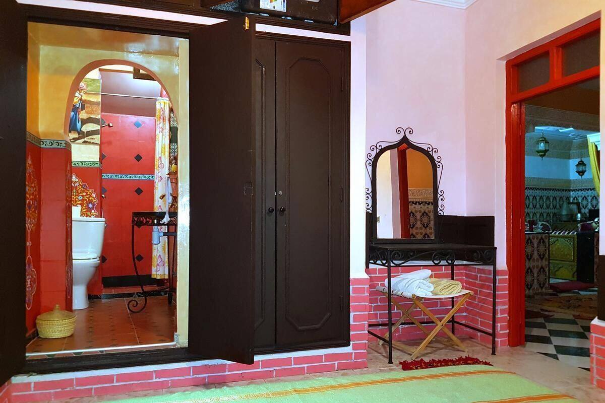 Une chambre avec un lit, une armoire, un miroir et une petite table.