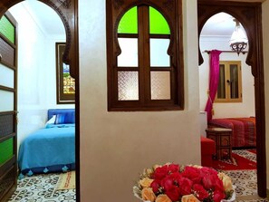 A room with a bed, a window with a green view, and a vase with flowers. - Riad Konouz (Marrakech)
