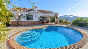 A swimming pool with a tiled edge, a patio with outdoor furniture, and a house with a tiled roof and white walls. - Finca Higueron Cómpeta by Ruralidays (Málaga)