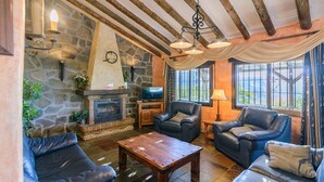 A cozy living room with stone walls, a fireplace, leather sofas, and a wooden coffee table. - Finca Higueron Cómpeta by Ruralidays (Málaga)