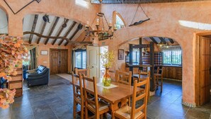 A spacious dining area with a wooden table and chairs, surrounded by arched ceilings and rustic decor. - Finca Higueron Cómpeta by Ruralidays (Málaga)