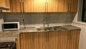 A kitchen with wooden cabinets, a microwave, a gas stove, and a double sink.