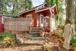 A red cabin with a wooden deck, a front porch, and a statue of an angel.