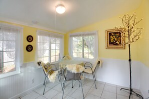 A dining area with a round table, four chairs, and a floor lamp.