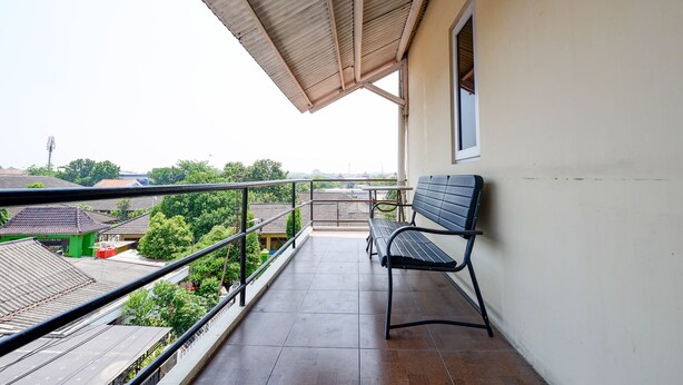 Ein Balkon mit einer Sitzbank, einer Geländer und Blick auf umliegende Gebäude und Grünflächen.