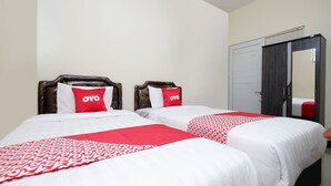 Ein Hotelzimmer mit zwei Betten, jeweils mit einer roten und weißen Tagesdecke und passenden Kissen.