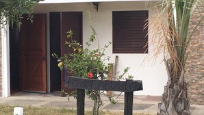 Un banco de madera con la inscripción “to del Pueblo” frente a un edificio con puerta y ventanas.