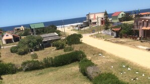 Un barrio costero con casas, un sendero de tierra y vista al océano.
