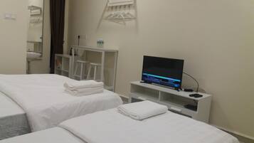 Une chambre d’hôtel avec deux lits, une télévision, une petite table et un miroir.