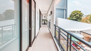A corridor with glass doors and windows, leading to a balcony with outdoor furniture. - OYO 1742 Safa Alya (Bekasi)