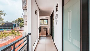 A narrow corridor with a tiled floor, a metal railing on one side, and a door on the other. There is a window with a view of the outside, and a sign on the wall. - OYO 1742 Safa Alya (Bekasi)