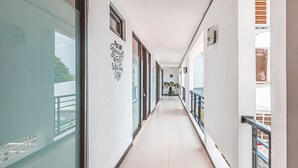 A corridor with glass doors, a potted plant, and a sign on the wall. - OYO 1742 Safa Alya (Bekasi)