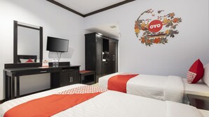 Ein Hotelzimmer mit zwei Betten, einem Fernseher, einem Kleiderschrank und einer Wanddekoration.