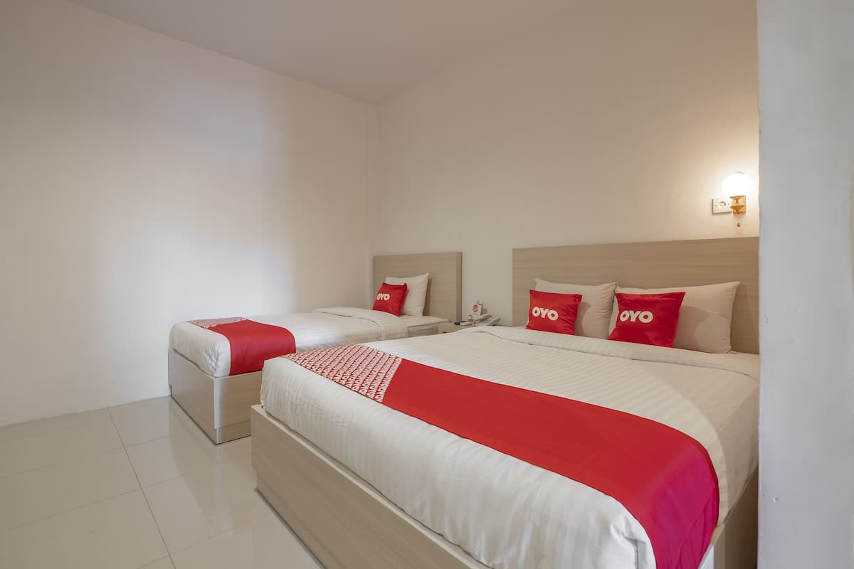 Une chambre d’hôtel avec deux lits, chacun recouvert d’une courtepointe rouge et blanche, et agrémentée d’oreillers assortis.