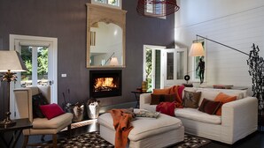 Un salon chaleureux avec une cheminée, des fauteuils confortables et un grand miroir.