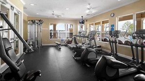 A gym with cardio equipment, weight machines, and a mirrored wall. - This amazing 6 Bedroom property with a lake view is spacious and newly furnished (Kissimmee)