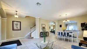 A spacious living room with a staircase, a dining area, and a kitchen in the background. - This amazing 6 Bedroom property with a lake view is spacious and newly furnished (Kissimmee)
