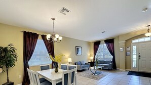 A living room with a dining table, two sofas, a chandelier, and a potted plant. - This amazing 6 Bedroom property with a lake view is spacious and newly furnished (Kissimmee)