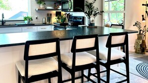 Una cucina moderna con isola centrale, sgabelli da bar, un forno a microonde e diversi oggetti decorativi.