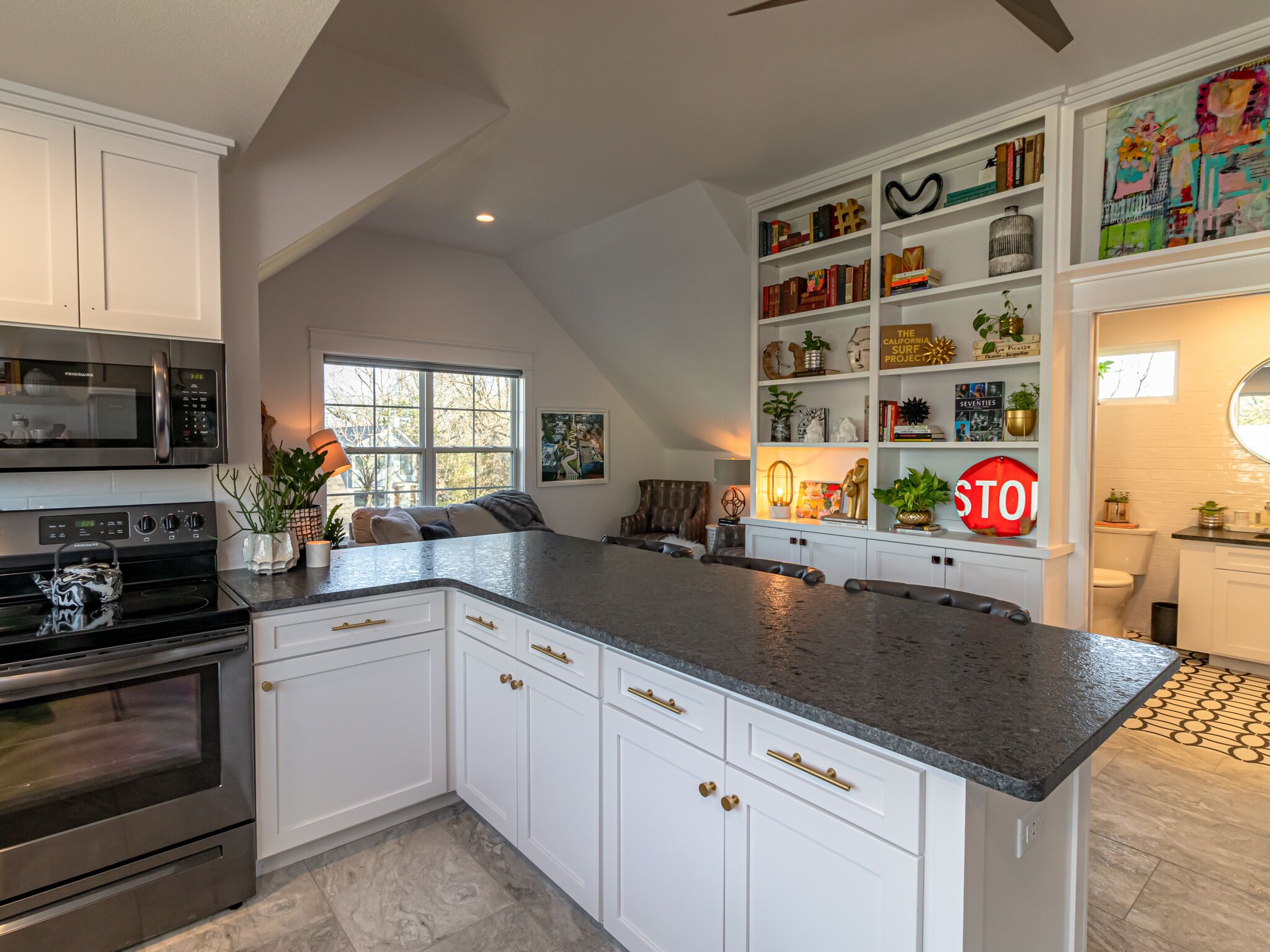 A modern kitchen with white cabinetry, a granite countertop, and stainless steel appliances.