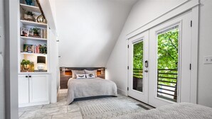Camera da letto con un letto, una libreria e una porta vetrata scorrevole su un balcone.