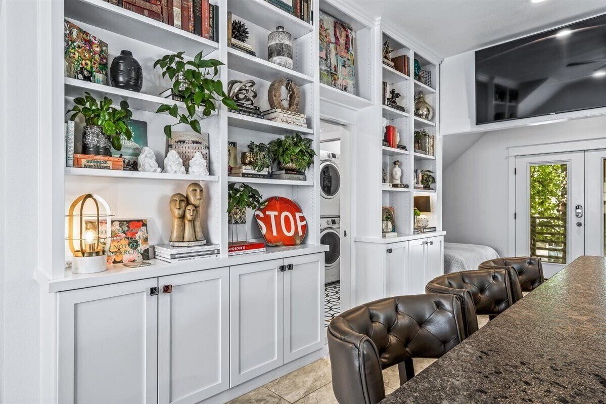 A modern kitchen with white cabinetry, a granite countertop, and a dining area with leather chairs.