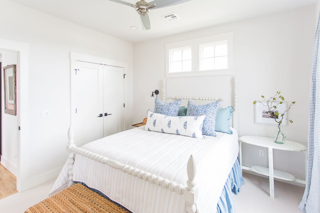 Un dormitorio con cama, mesita de noche, ventilador de techo, ventana y puerta.