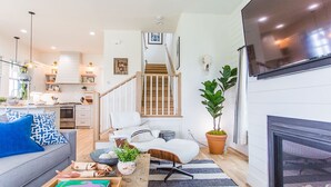 Un salon moderne avec un canapé, une table basse et une cheminée. Un escalier mène à l’étage supérieur.