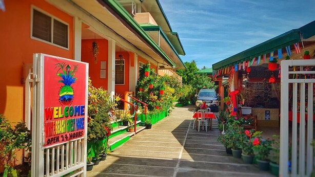 Un bâtiment aux couleurs vives, agrémenté d’une pancarte « Bienvenue », de places assises en plein air et de plantes en pot.
