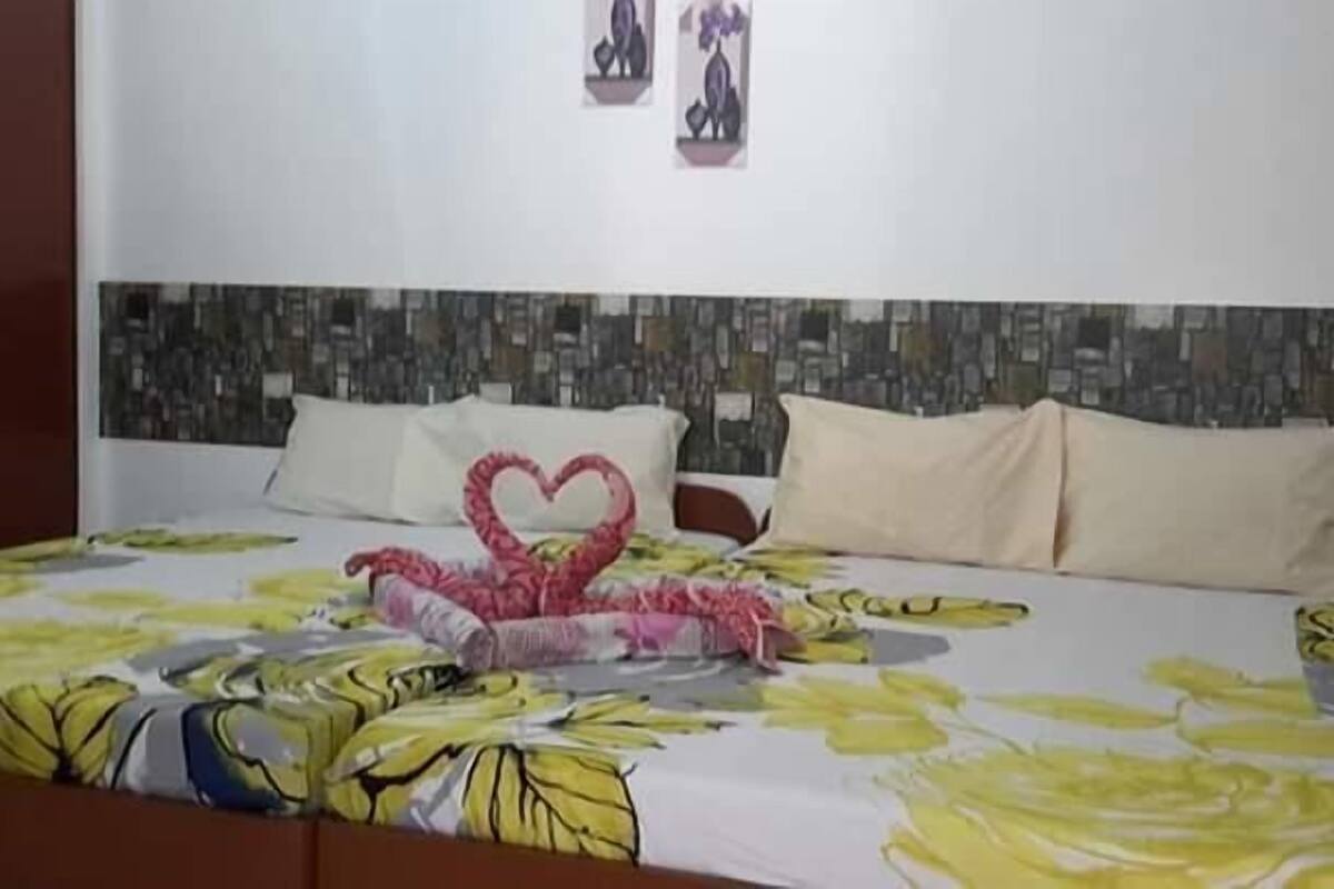 A hotel room with a bed, a headboard with a patterned design, and two wall-mounted pictures.