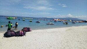 Une plage où l’on voit de nombreux bateaux et des gens dans l’eau.