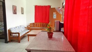 Una sala de estar con un sofá, una mesa de madera y una planta en maceta.