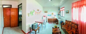 Espaço compacto com cozinha compacta, área de refeições e sala de estar com sofá e cadeiras.