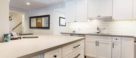Una cocina moderna con armarios blancos, una isla grande con fregadero y un salpicadero de azulejos.