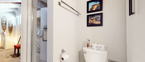 A bathroom with a toilet, a towel rack, and two framed pictures on the wall.