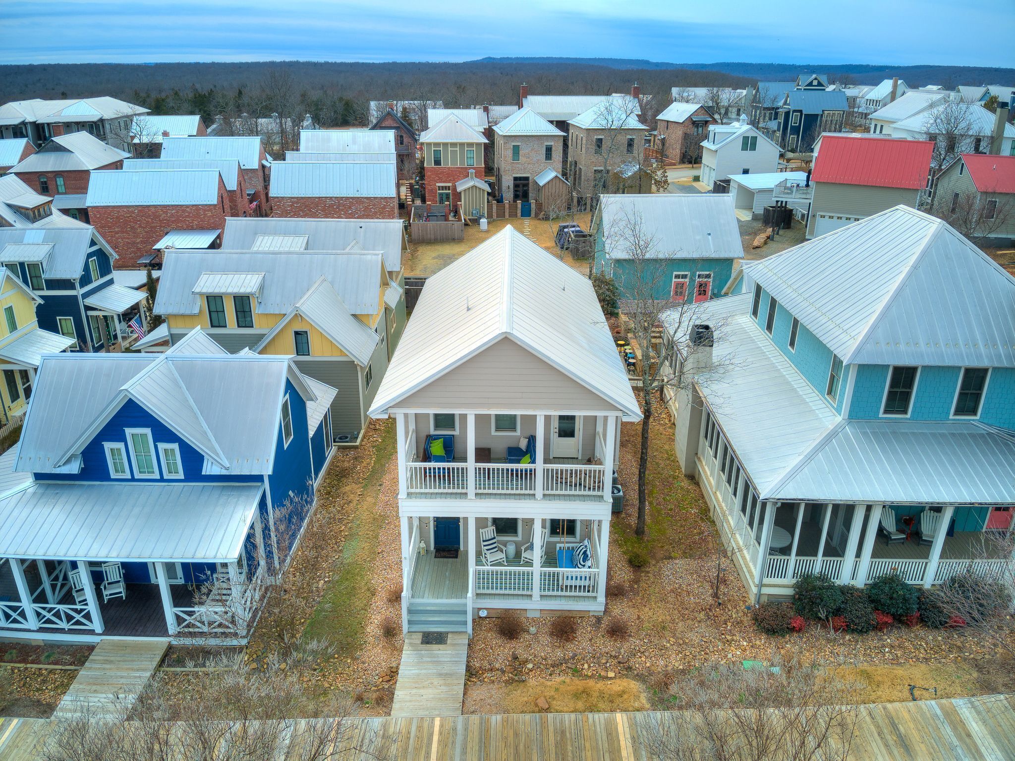 Un quartier résidentiel composé de différentes maisons, dont une grande maison à deux étages dotée d’un porche et d’une véranda couverte à l’avant.